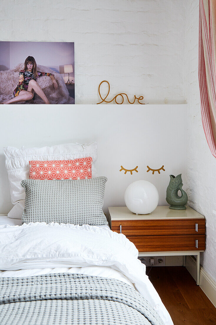 Bed with assorted throw pillows and bedside table with decorative objects