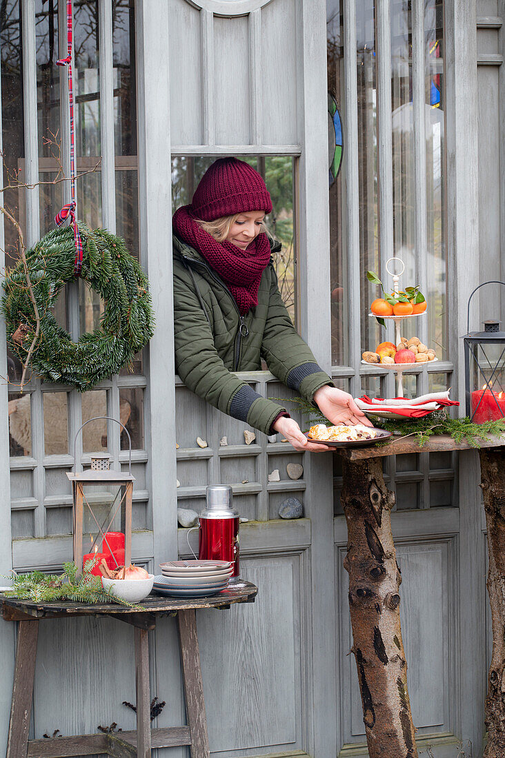 Woman dressed in winter handing plate with strudel through window