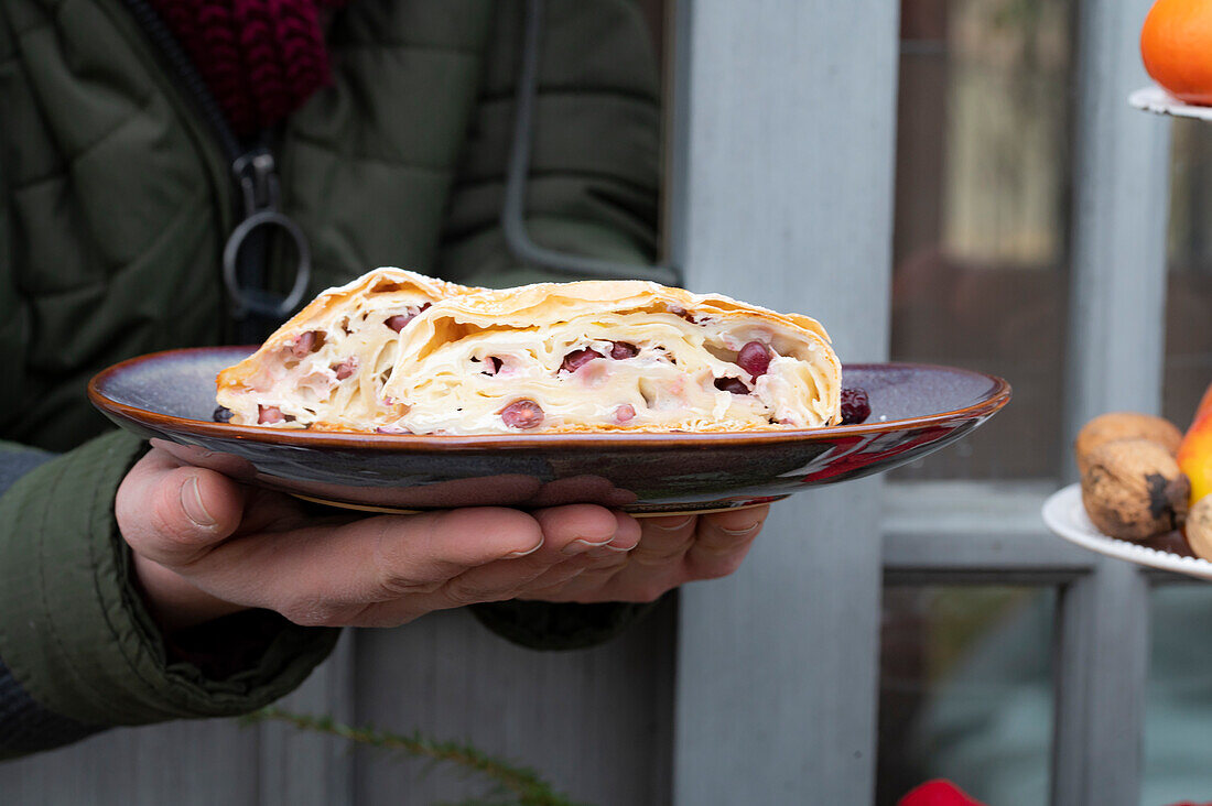 Hands holding plate with curd strudel