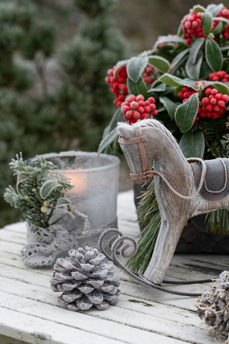 Christmas decoration with skimmia, lantern, small rocking horse, and cone