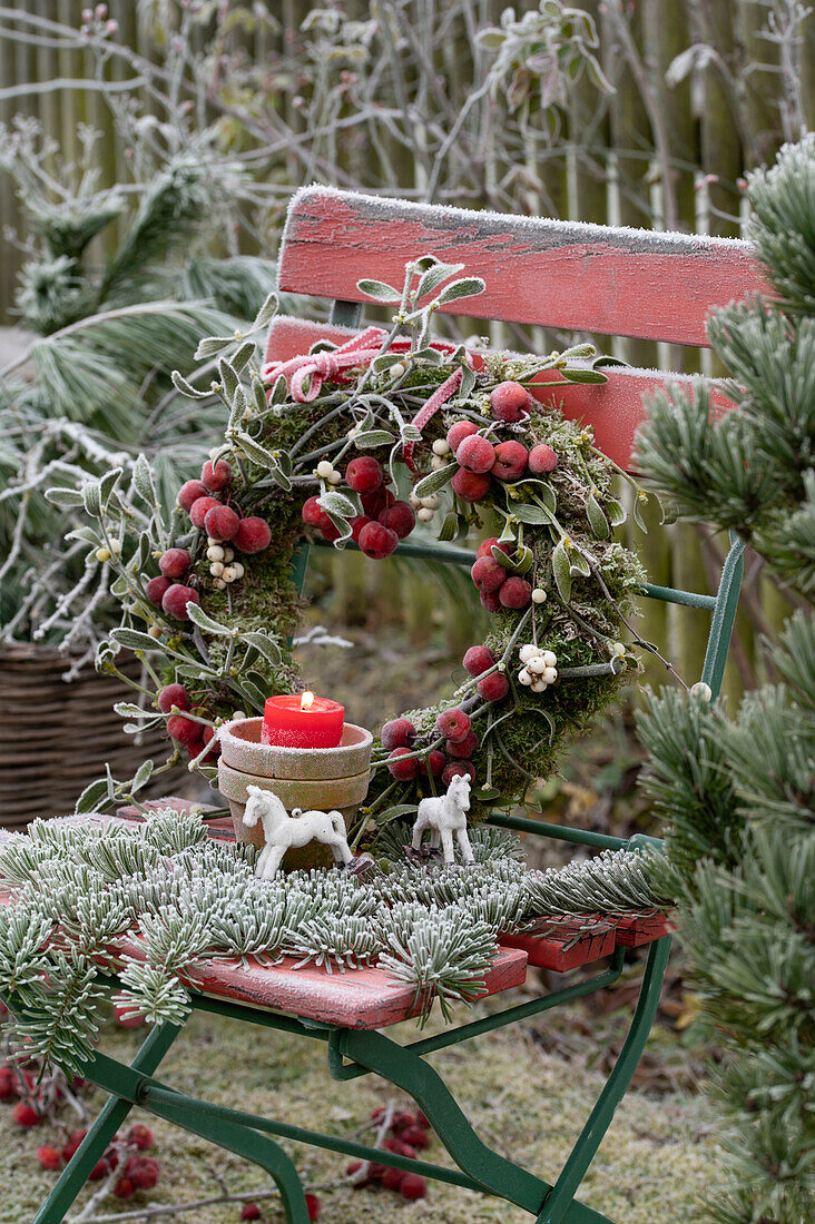 Wreath of moss ornamental apples and mistletoe on a garden chair