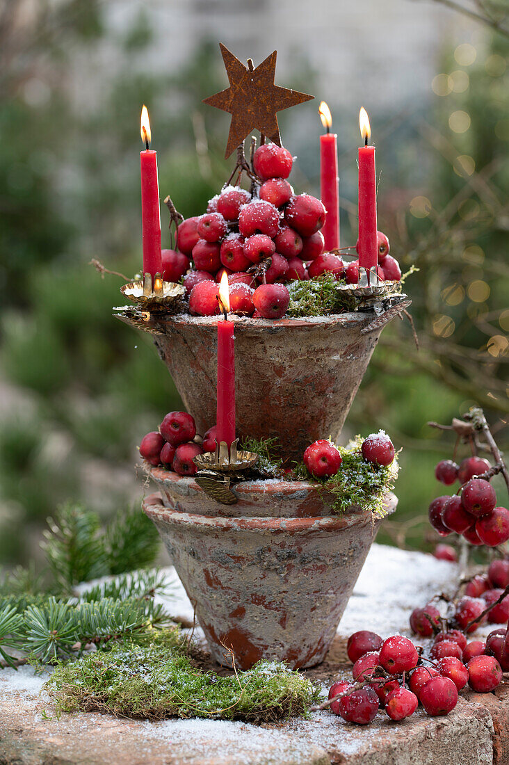 Turm aus Terrakottatöpfen mit Zieräpfeln und Kerzen als Adventskranz
