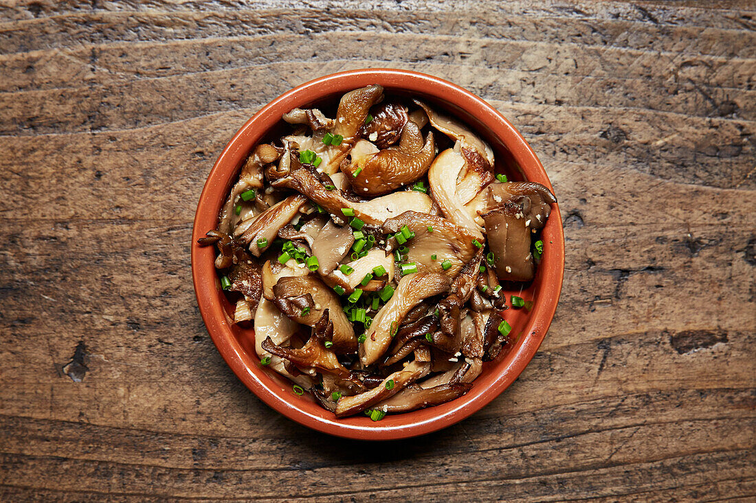 Mushrooms and chives in a terracotta tapas dish