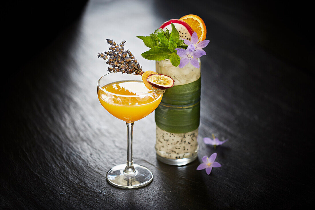 Two elegantly garnished cocktails on a dark surface