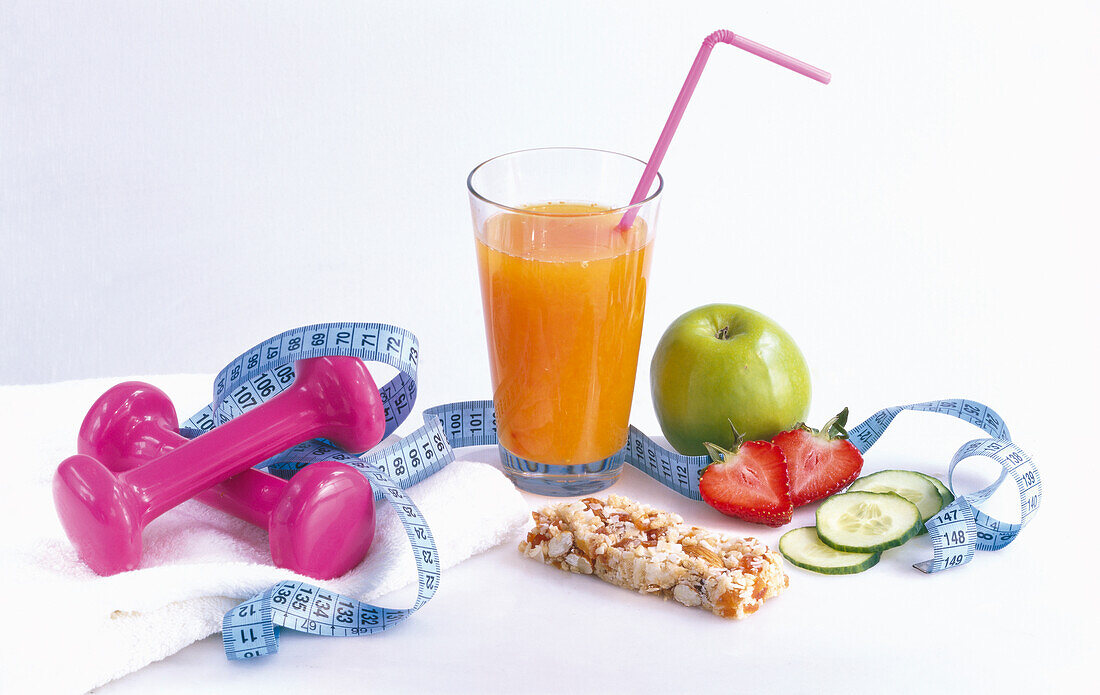 Slimming cure: A glass of fruit juice, granola bar, apple, strawberry, cucumber, dumbbells, and tape measure