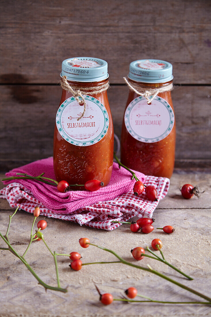 Rosehip spice sauce with homemade labels, surrounded by rosehips