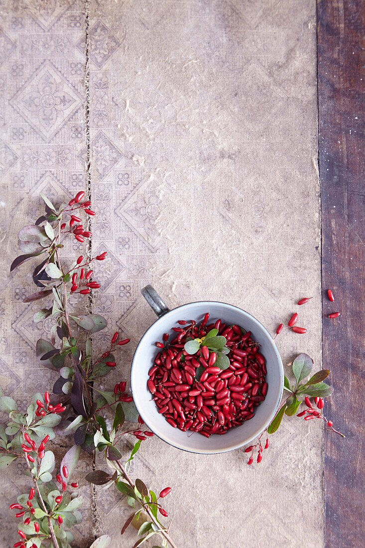 A bowl of barberries beside barberry twigs