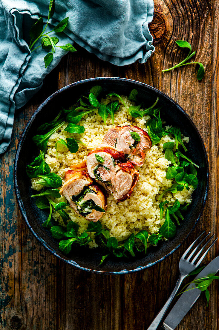 Chicken wrapped in sage-bacon coat with butter couscous and lamb's lettuce