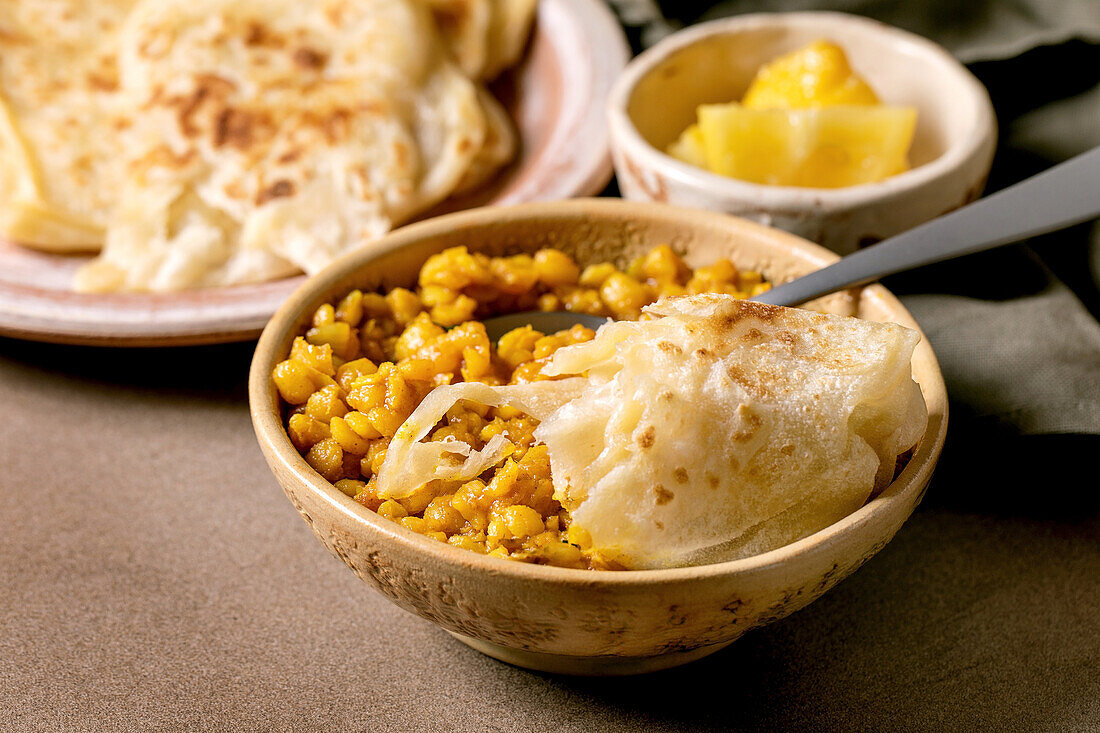 Traditionelles indisches gelbes Erbsen-Dal mit Roti und Zitrone