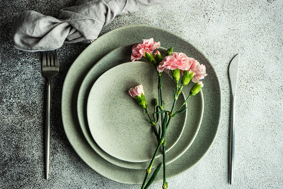 Minimalistische Tischdekoration in grauen Farben, dekoriert mit rosa Nelken