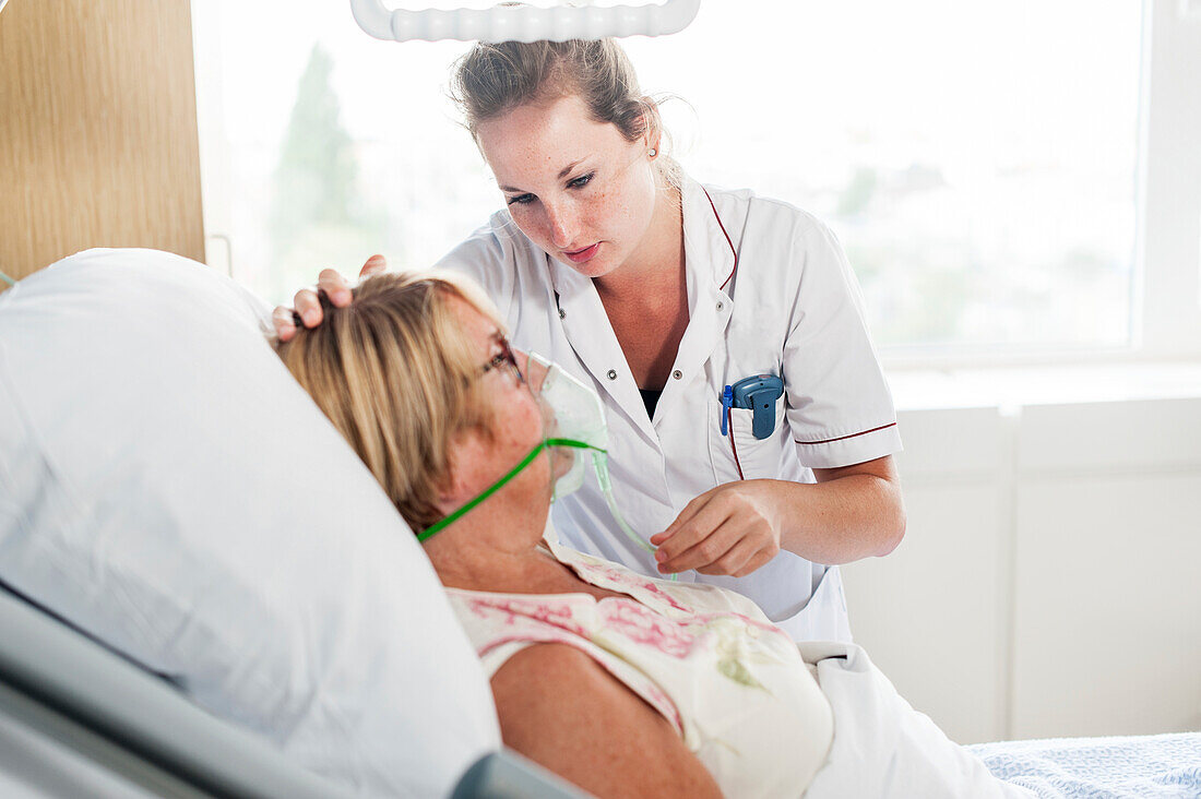 Nurse applying an oxygen mask onto an elderly female patient