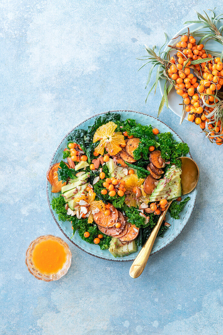 Kale salad with oranges, roasted sweet potatoes, almonds, and sea buckthorn dressing