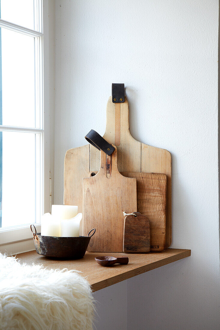 Wooden cutting boards and pot with candle on window sill