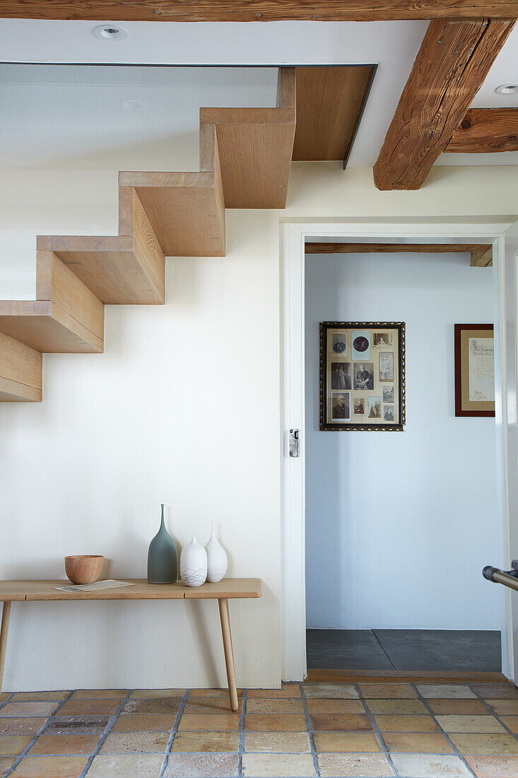 Wooden bench with ceramic pots under stairs