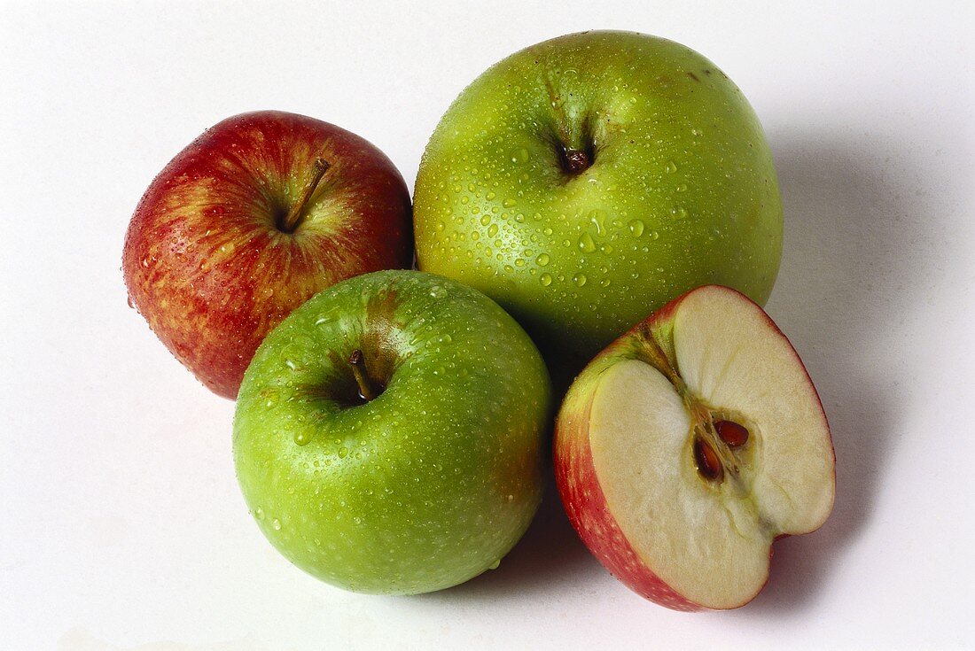 Zwei grüne Äpfel, ein roter & rote Apfelhälfte