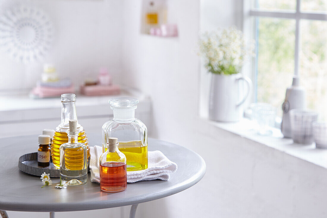 Oils in vials and corked bottles on a round metal table, essential oils next to them