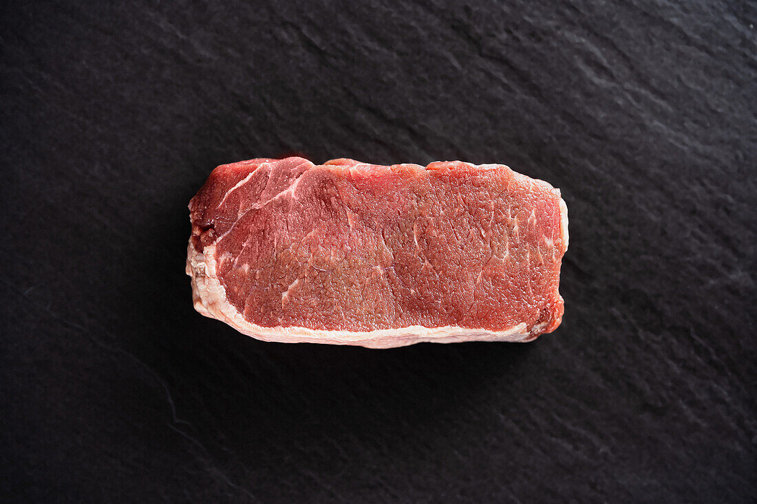 Piece of raw beef steak on a black background