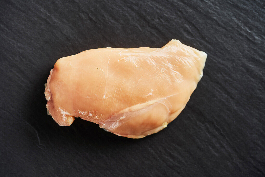 Raw chicken breast on a black background