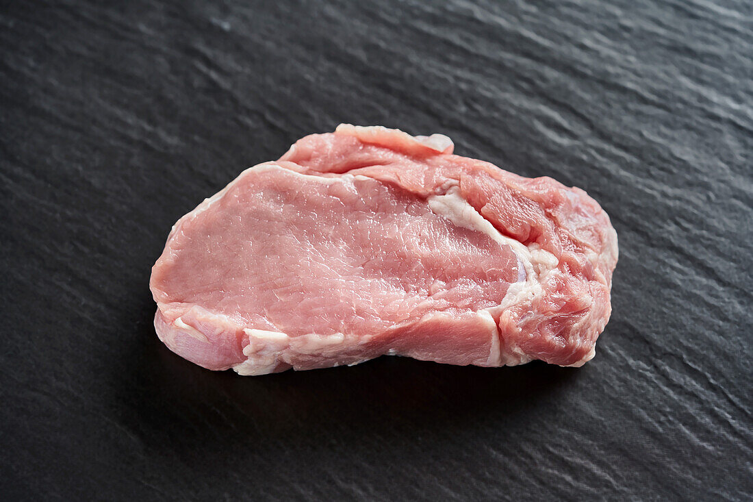 Rohes Schweinefleisch auf schwarzem Untergrund