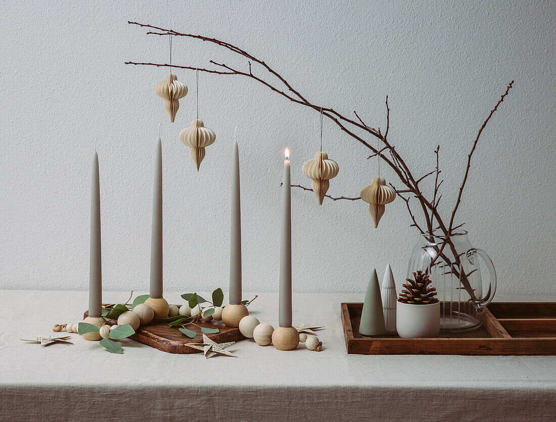 Kerzen, Holzperlen und Zweige mit Weihnachtsschmuck aus Papier