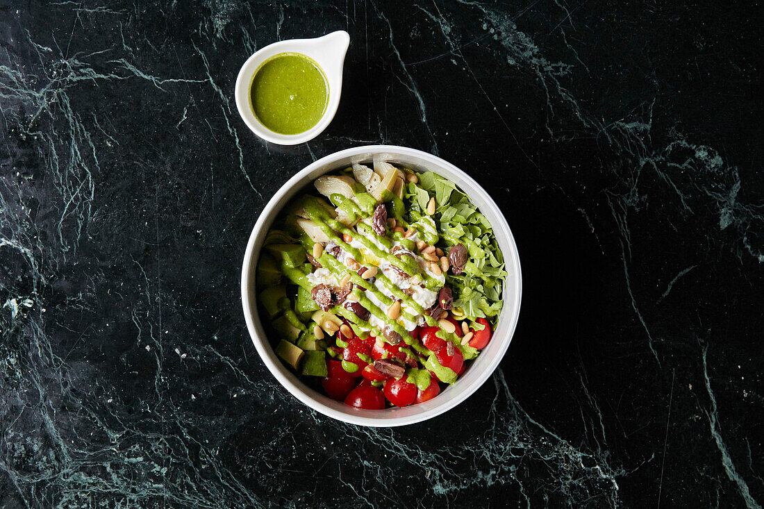 A healthy bowl with avocado, tomato, artichokes and olives to take away