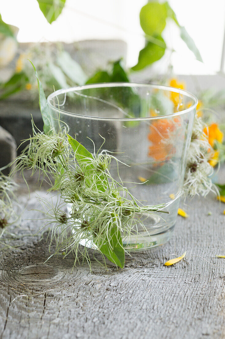 Glasvase umwickelt mit Clematis-Fruchtständen