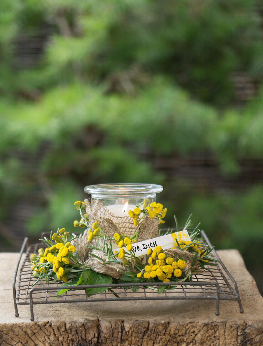 Weckglas als Windlicht umwickelt mit Rainfarn (Tanacetum vulgare), Brombeerblätter (Rubus), Rosmarin und Sackband