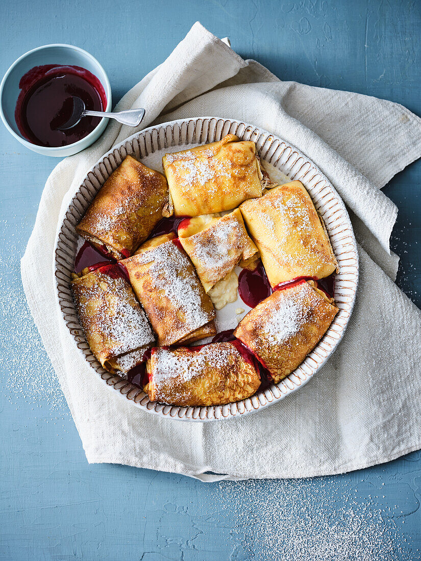 Oven-baked Jewish cheese blintzes with red fruit jelly sauce