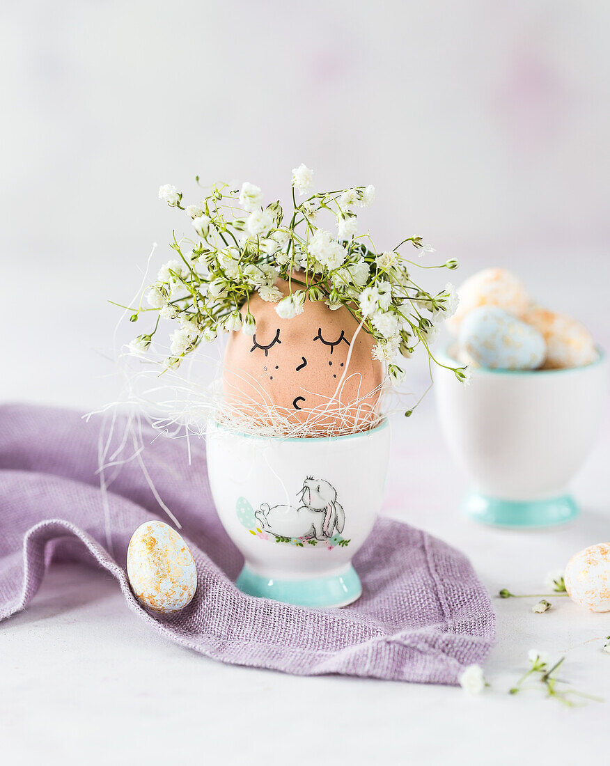 Breakfast egg with a face and baby's breath (Gypsophila) in an egg cup for Easter