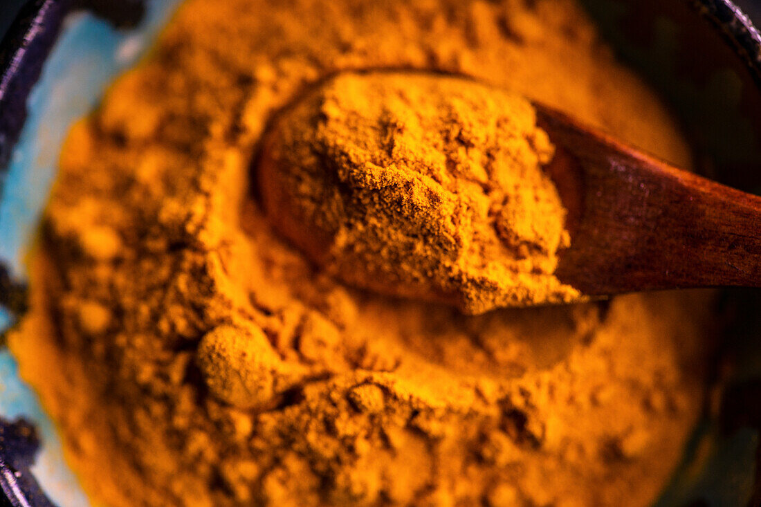 Turmeric powder with a wooden spoon (close up)
