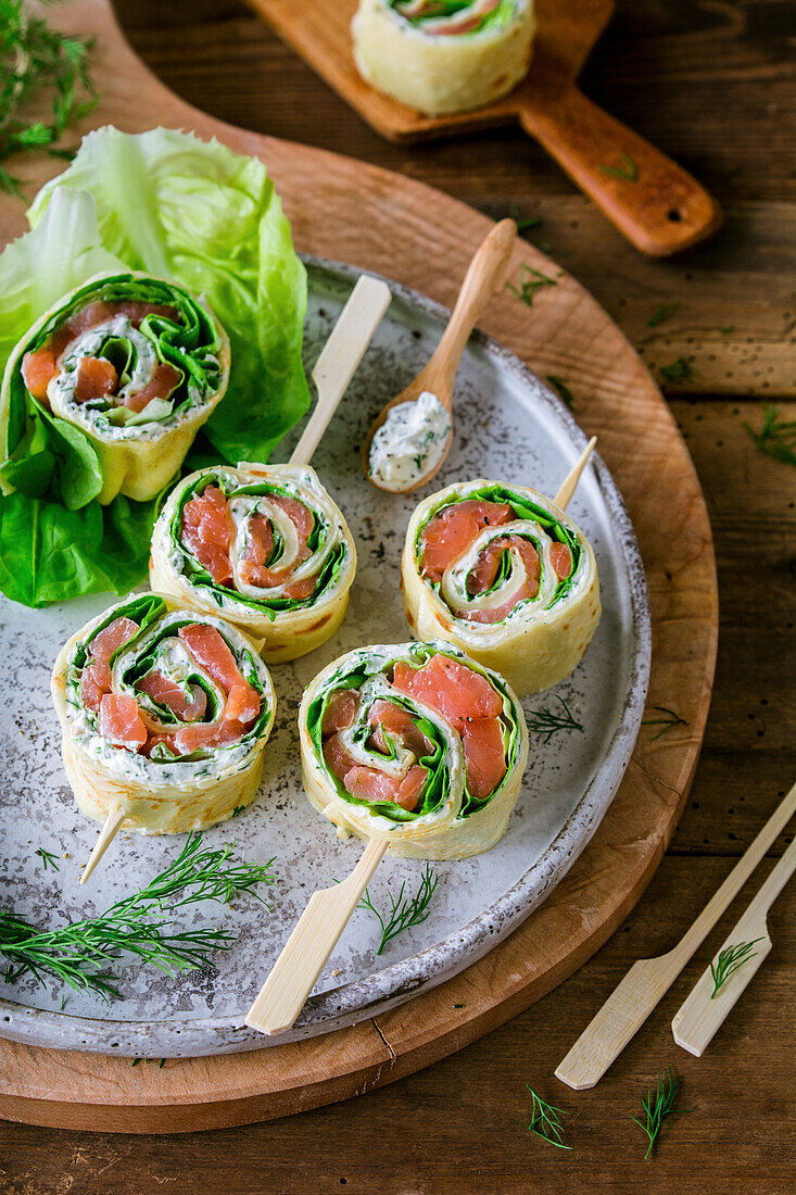 Smoked salmon rolls with cream cheese and lettuce on sticks