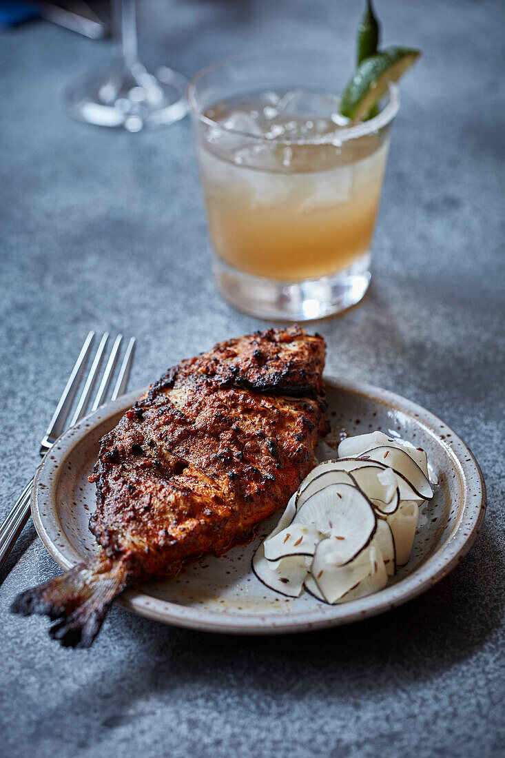 Indian spiced fried fish with an orange cocktail