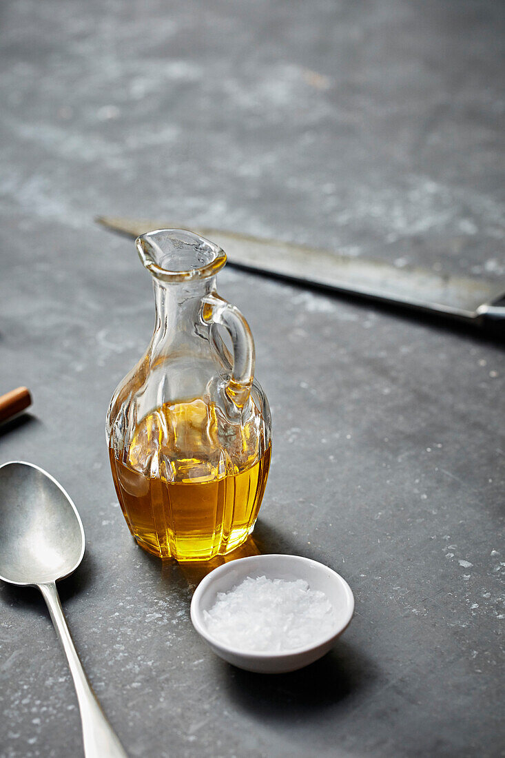 Olivenöl in einer Glasflasche daneben Meersalz im Schälchen