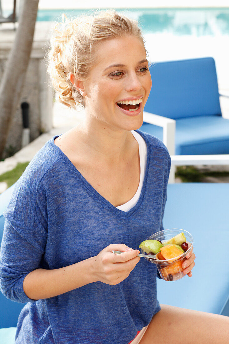 Blonde woman in blue shirt with dessert in hand