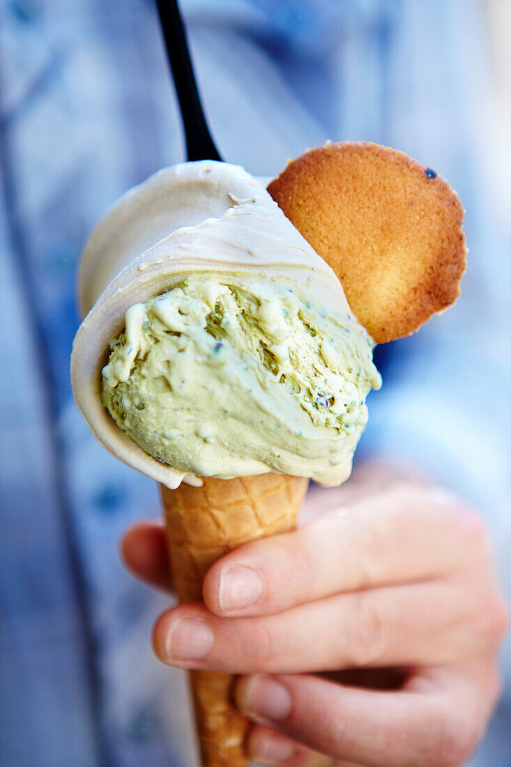 Hand held ice cream cones with pistachio and hazelnut ice cream