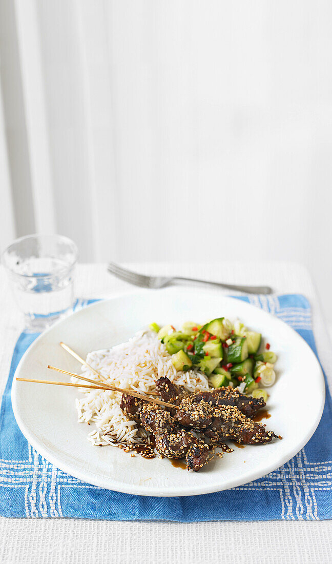 Oriental beef skewers with cucumber salad and rice