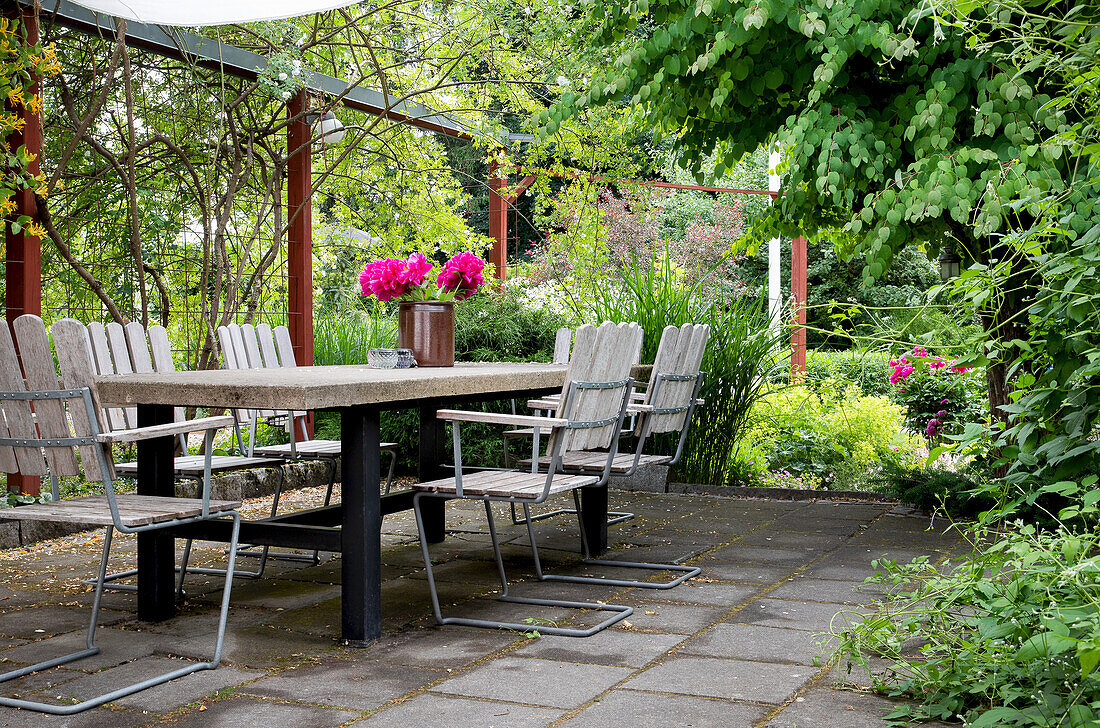 Terrasse mit Gartenmöbeln und Blumenarrangement im Sommer