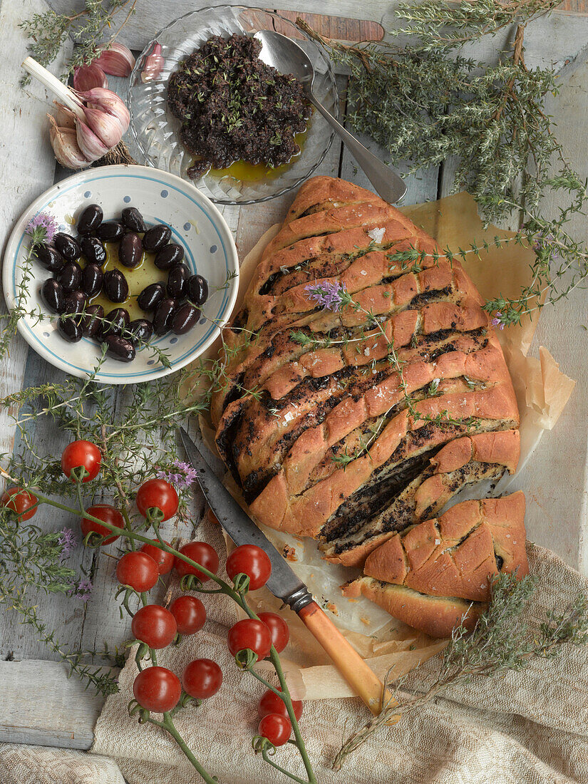 Stillleben mit Olivenbrot, Olivenpesto, Oliven und Tomaten
