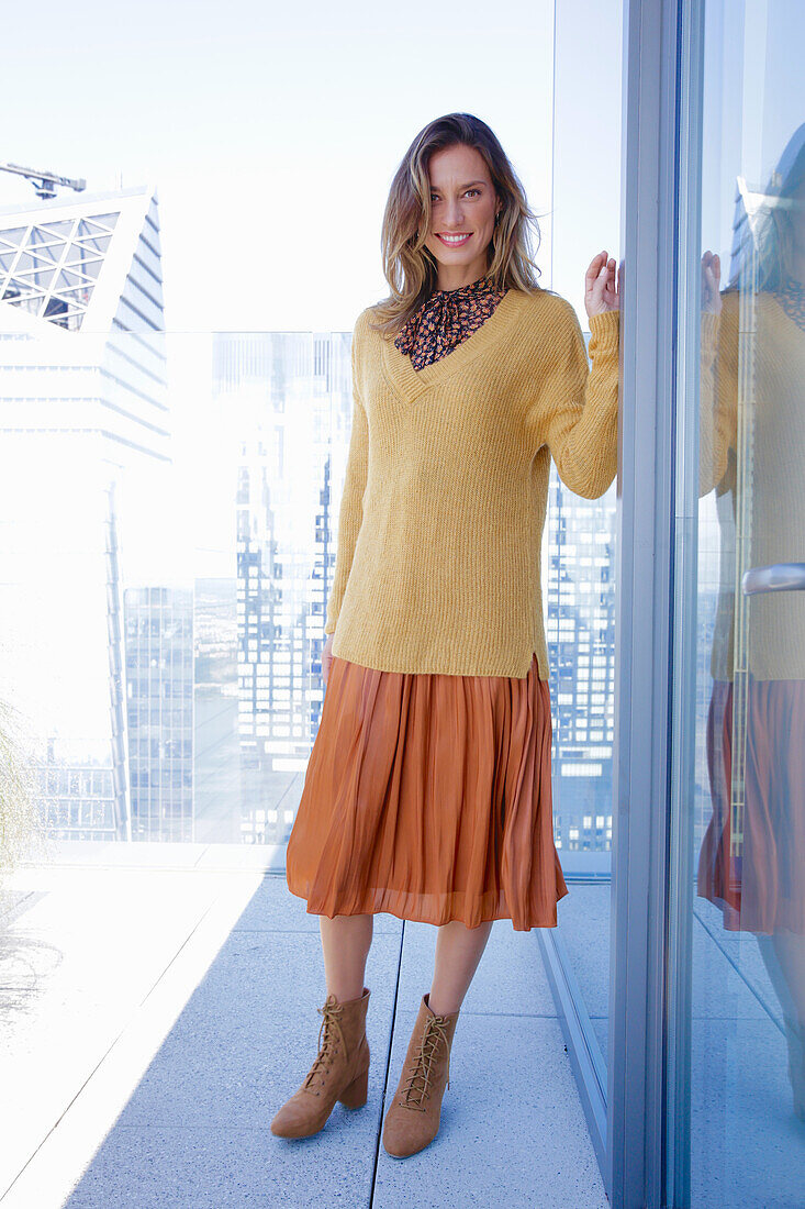 A long-haired woman wearing an orange skirt and a yellow knitted jumper
