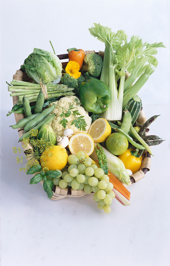 Kleiner Korb mit Obst und Gemüse auf hellem Untergrund