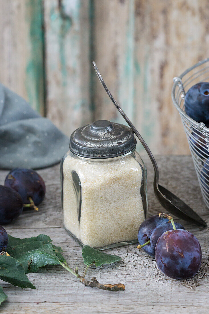 Cane sugar in vintage jar and fresh plums