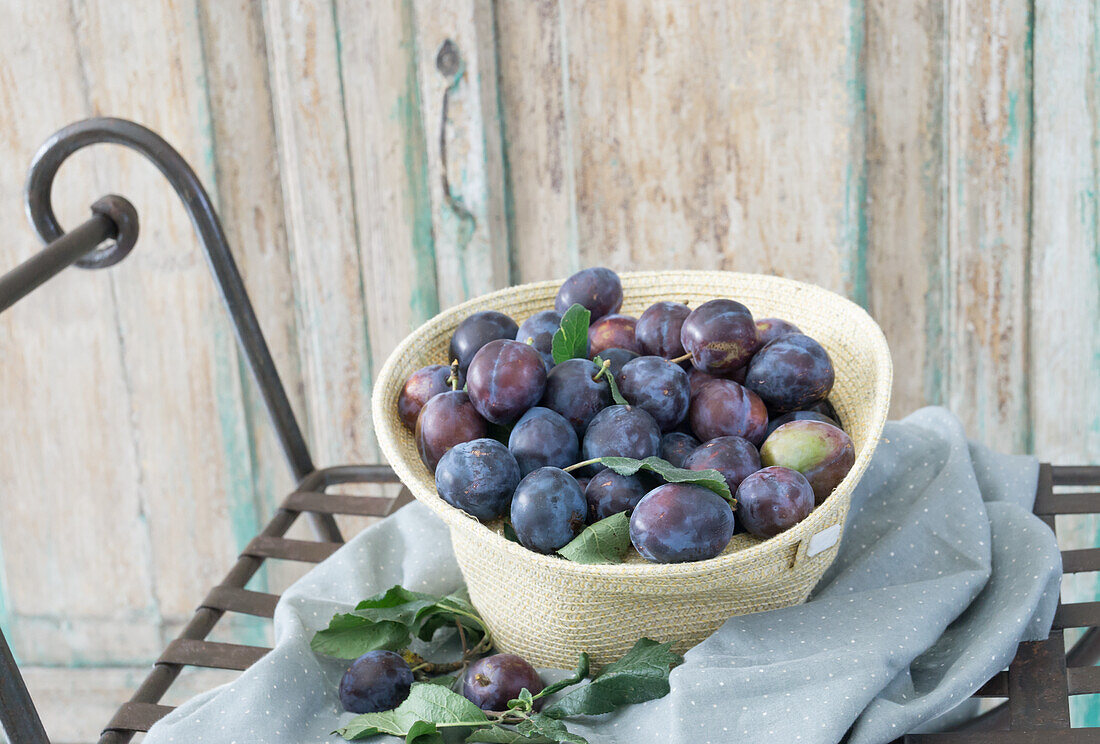 Fresh plums in straw hat