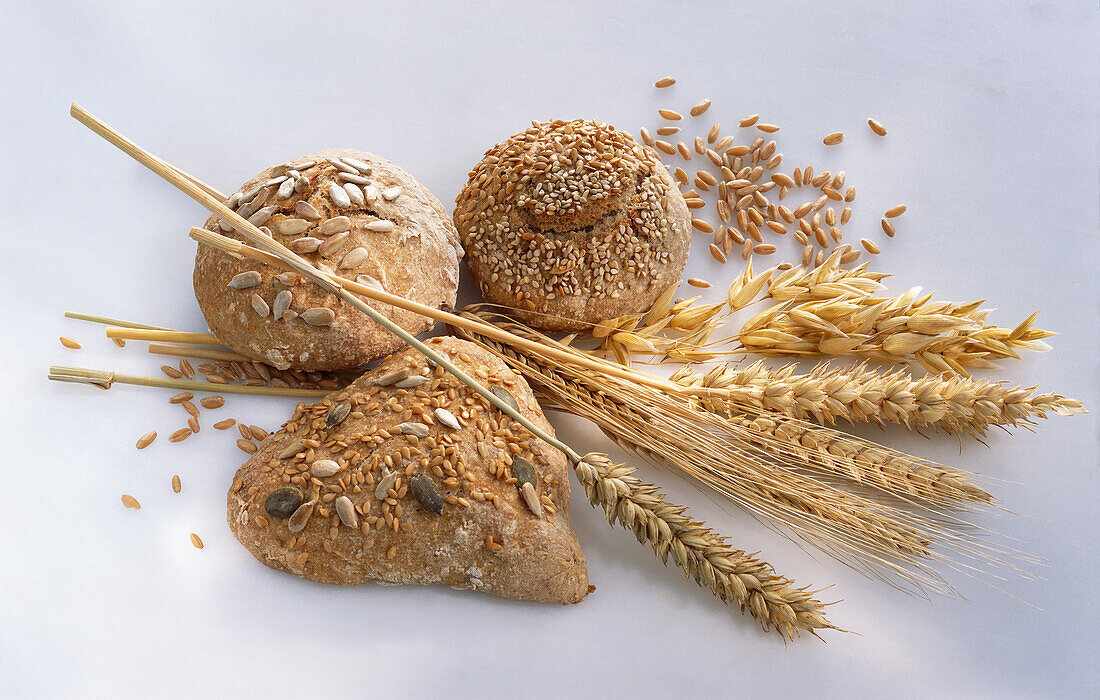 Three wholemeal rolls, ears of cereal, and cereal grains
