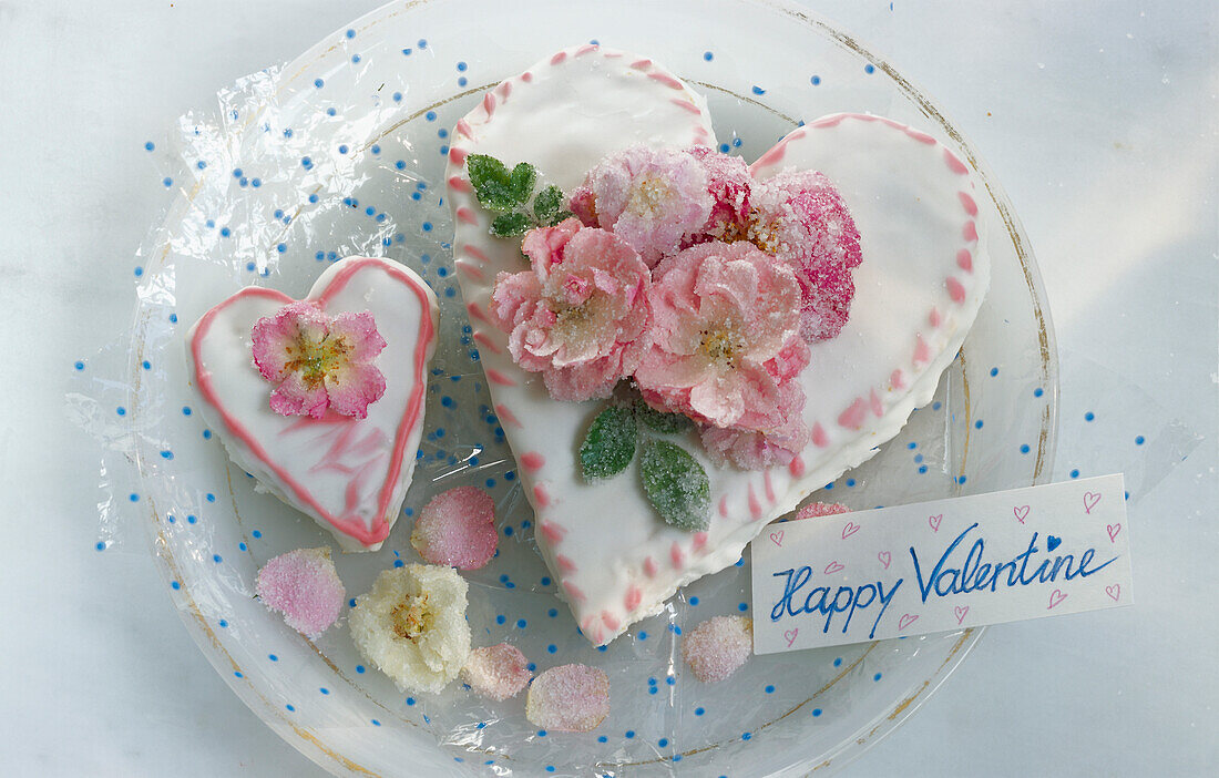Zwei herzförmige Torten zum Valentinstag, mit gezuckerten Rosenblüten