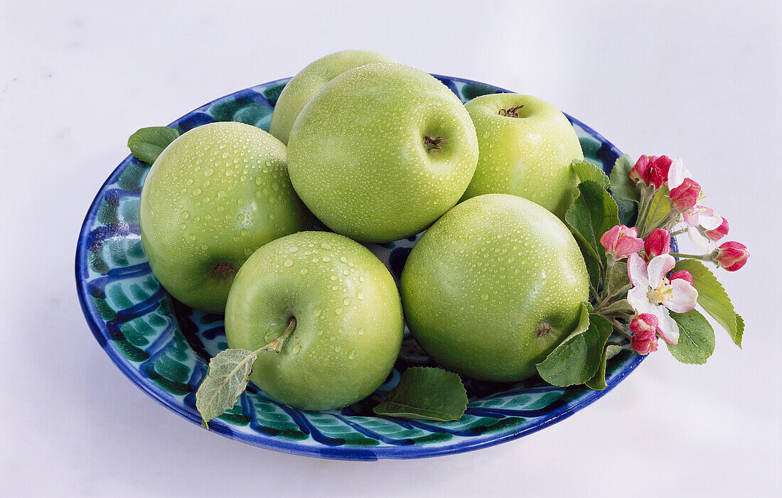 Bowl with green apples and apple blossoms