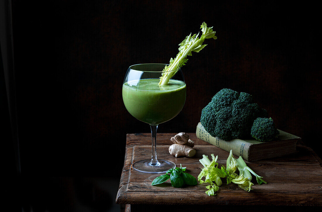 Green vegetable smoothie on a wooden table against a black background
