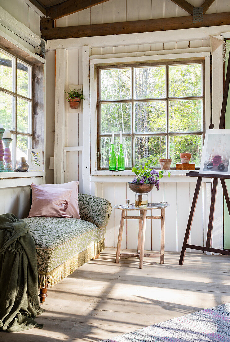 Light-colored garden shed with rustic bench and window decoration