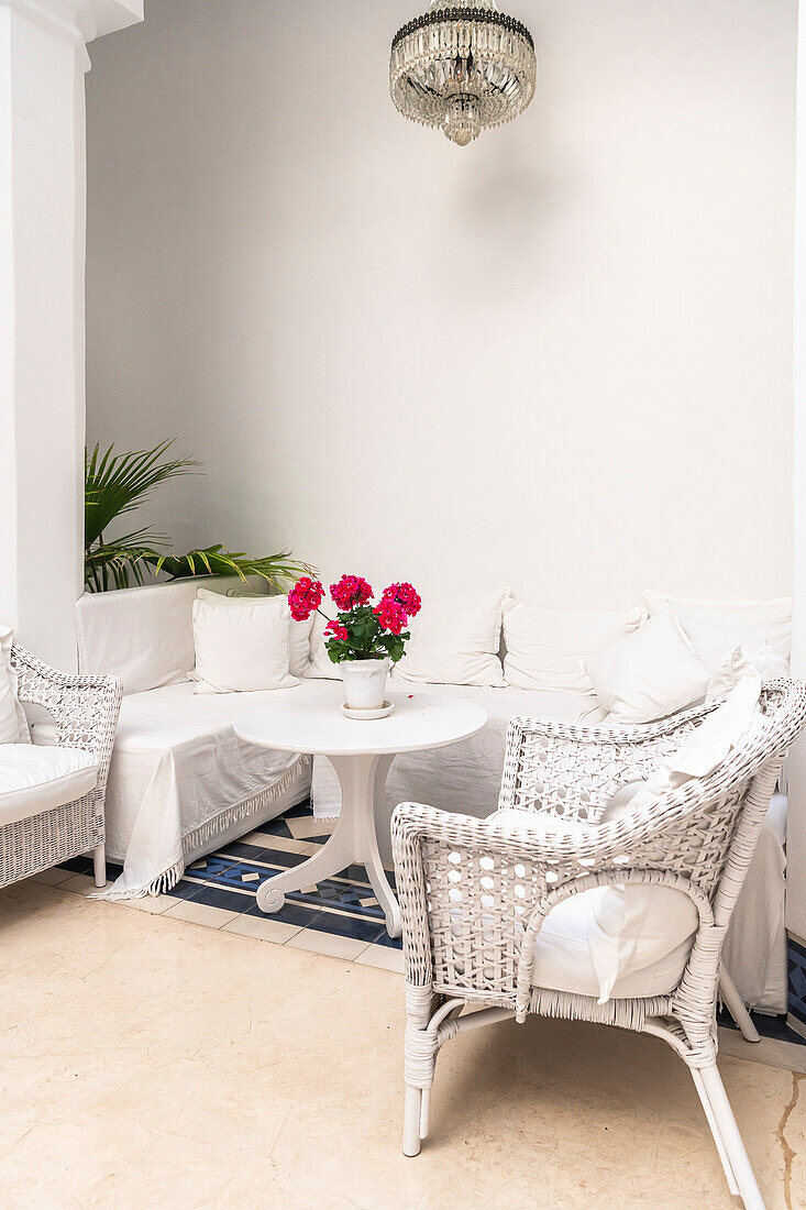 White rattan furniture in lounge corner and white table with pink flowers