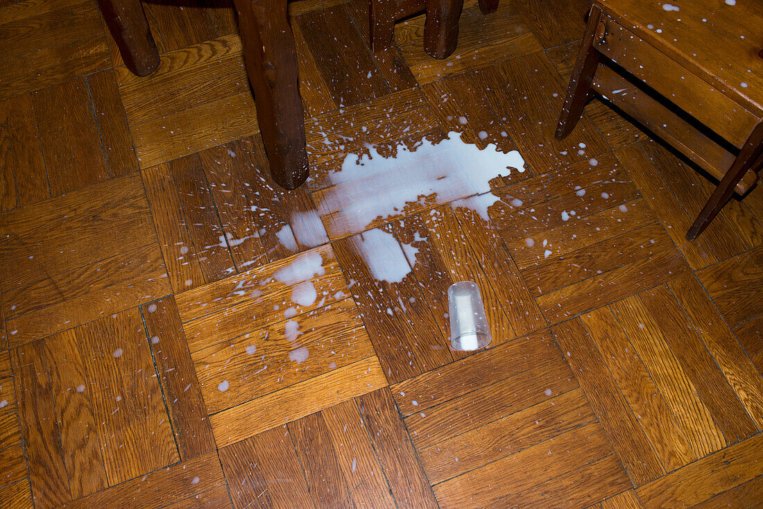 High Angle View of Plastic Cup of Milk dropped on Wood Parquet Floor