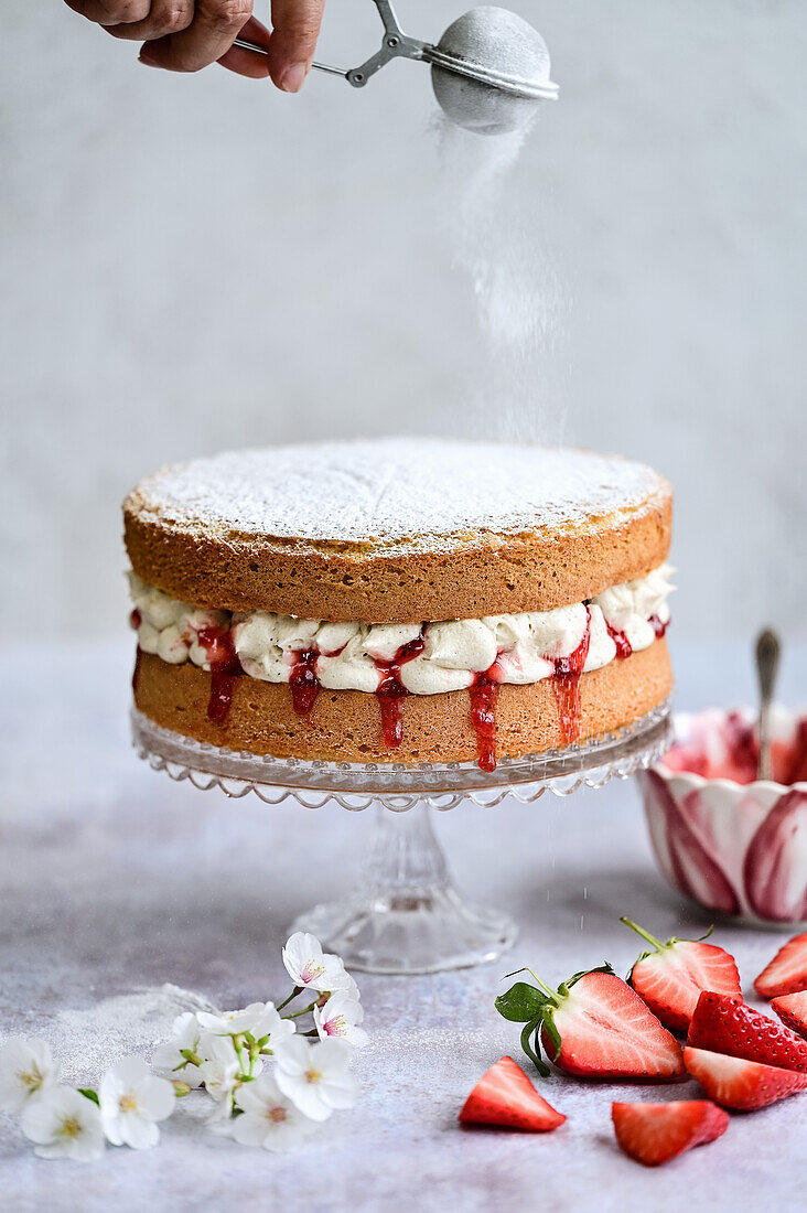Victoria Sponge Cake - Biskuitkuchen mit Sahne und Erdbeeren, mit Puderzucker bestäuben